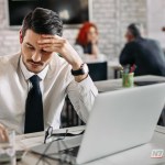 Mão de um profissional segurando uma caneta sobre um documento de rescisão contratual ao lado de um calendário e uma calculadora.