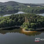 Vista aérea de uma grande ilha fluvial coberta por vegetação densa, cercada pelas águas extensas de um rio amazônico.
