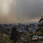 Vista panorâmica de uma cidade brasileira sob nuvens carregadas e chuva intensa, representando o clima tropical úmido.