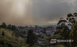 Vista panorâmica de uma cidade brasileira sob nuvens carregadas e chuva intensa, representando o clima tropical úmido.