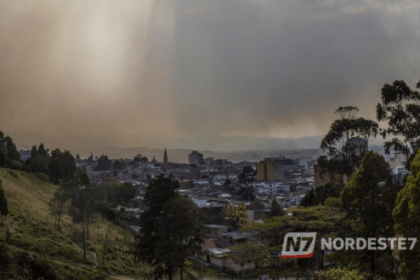 Vista panorâmica de uma cidade brasileira sob nuvens carregadas e chuva intensa, representando o clima tropical úmido.