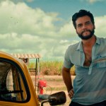 Estatueta dourada do Oscar em destaque ao lado de uma claquete de cinema com as cores da bandeira do Brasil.