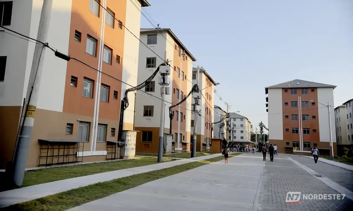 Fachada de conjunto habitacional popular do programa Minha Casa Minha Vida com chaves em primeiro plano, simbolizando a conquista da casa própria.