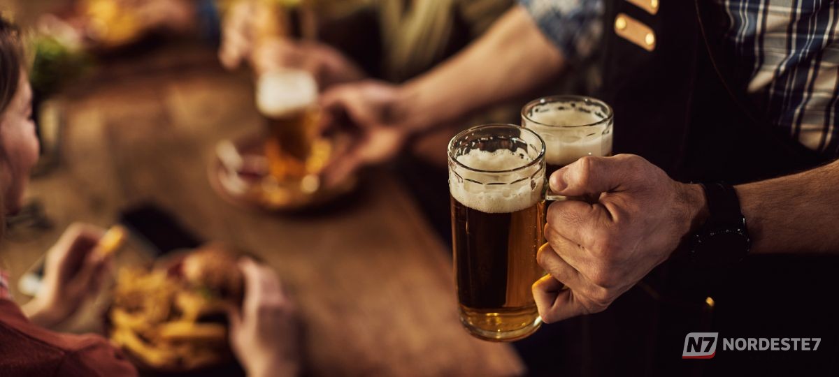 Close-up de latas de cerveja com rótulo 'zero álcool' em destaque em uma prateleira de supermercado.