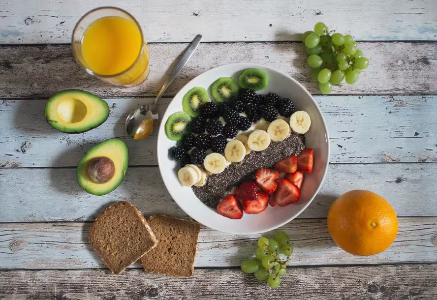 Variedade de frutas, legumes e verduras frescas coloridas dispostas sobre uma mesa, representando a recomendação nutricional da OMS.