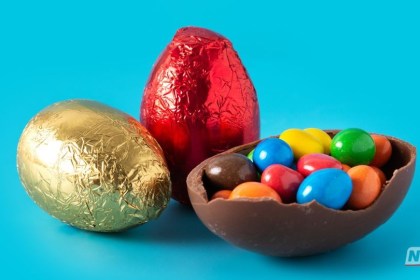 Cartão do programa Bolsa Família posicionado ao lado de um grande ovo de Páscoa de 1kg envolto em papel dourado.