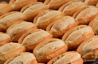 Vários pães do tipo marraqueta e hallulla empilhados em uma cesta de vime em uma padaria chilena.