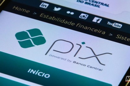 Smartphone exibindo o logotipo do PIX em um aplicativo de banco digital sobre uma mesa.