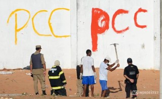 Montagem fotográfica exibindo as bandeiras dos Estados Unidos e do Brasil lado a lado, com silhuetas de soldados militares ao fundo em tom de mistério e tensão geopolítica.