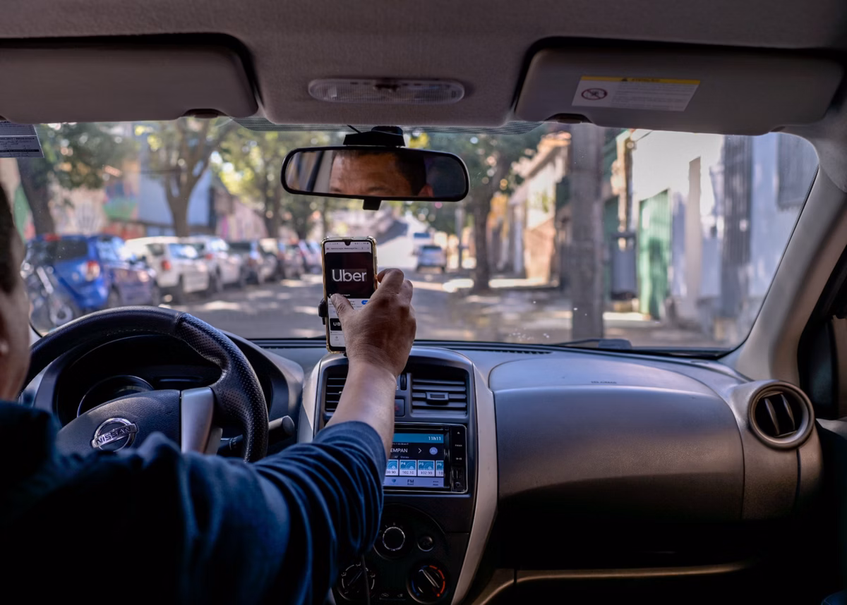 Motorista de aplicativo sorridente ao volante de um carro novo, representando o programa de financiamento do Governo Lula para condutores da Uber e 99.