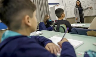 Fachada de uma escola com portão fechado e cadeado, simbolizando a suspensão das atividades escolares.
