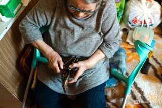 Idoso sorridente segurando smartphone e o cartão de benefício do INSS, representando a consulta ao saldo do pagamento extra.