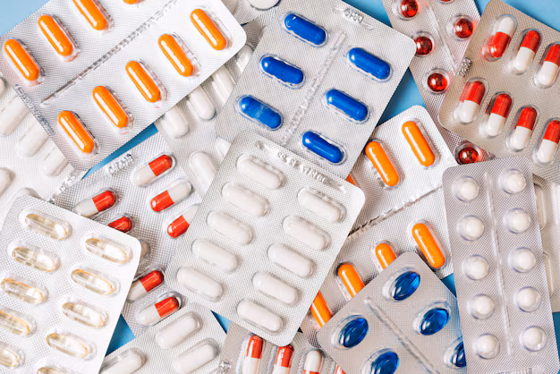 Mão segurando uma cartela de comprimidos e verificando o número do lote na embalagem, ilustrando o processo de conferência de medicamentos.