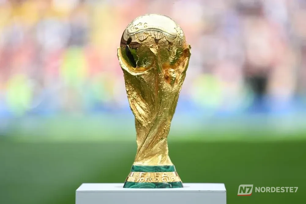 Estádio de futebol moderno sob iluminação dramática e céu cinzento, simbolizando a ameaça de adiamento dos jogos da Copa do Mundo de 2026.