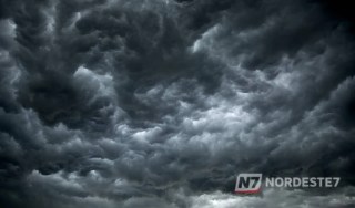 Nuvens escuras e densas de uma tempestade severa avançando sobre uma área urbana no Brasil, ilustrando o alerta meteorológico de ventos de 100 km/h.