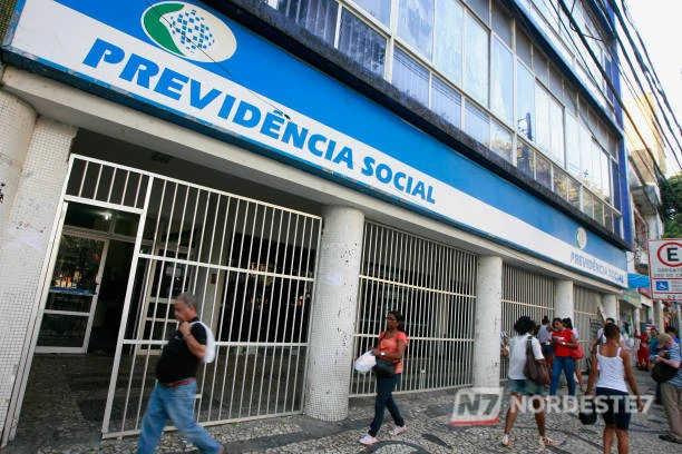 Foto de plano médio do presidente do INSS em um pronunciamento oficial, sorrindo ao anunciar novas medidas para aposentados e pensionistas.