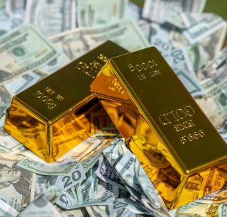 Barras de ouro brilhantes empilhadas em primeiro plano com cédulas de dólar americano desfocadas ao fundo, simbolizando a valorização do ouro frente à moeda americana.