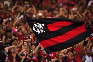 Ídolo histórico do Flamengo sorrindo durante coletiva, vestindo a camisa rubro-negra ao anunciar seu retorno ao clube.