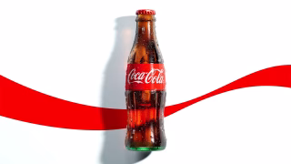 Lata de Coca-Cola Zero sob iluminação de estúdio ao lado de um copo com gelo e refrigerante.