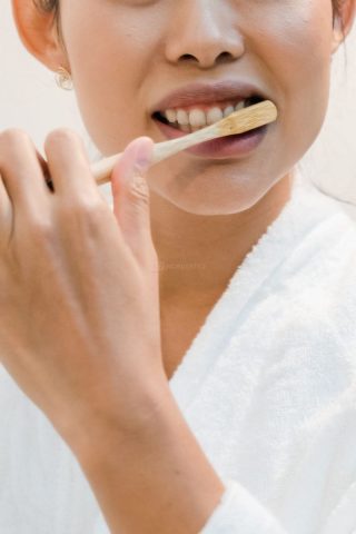 Pessoa escovando os dentes de forma detalhada com escova de cerdas macias, representando o tempo correto de higienização bucal.