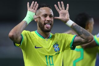Jogador Neymar Jr. com expressão pensativa em campo de futebol, vestindo uniforme esportivo.
