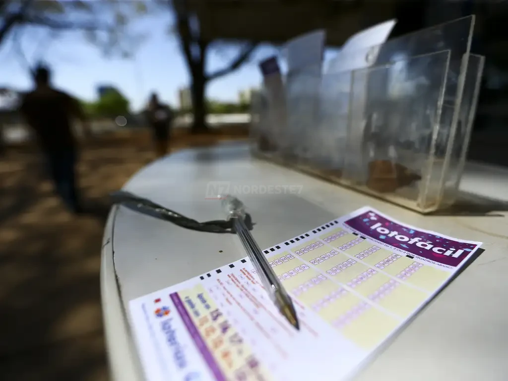 Volante oficial de aposta da Lotofácil com caneta preta ao lado para marcação dos números do concurso 3764.